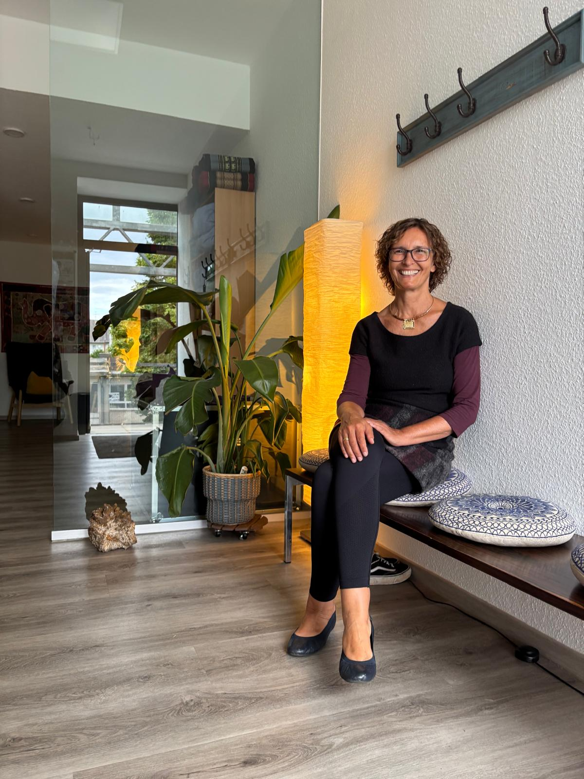 Gesa Hecken im hellen Praxisflur mit Pflanzen und warmer Beleuchtung
